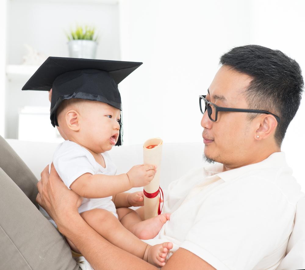 Man holding baby in graduation hat