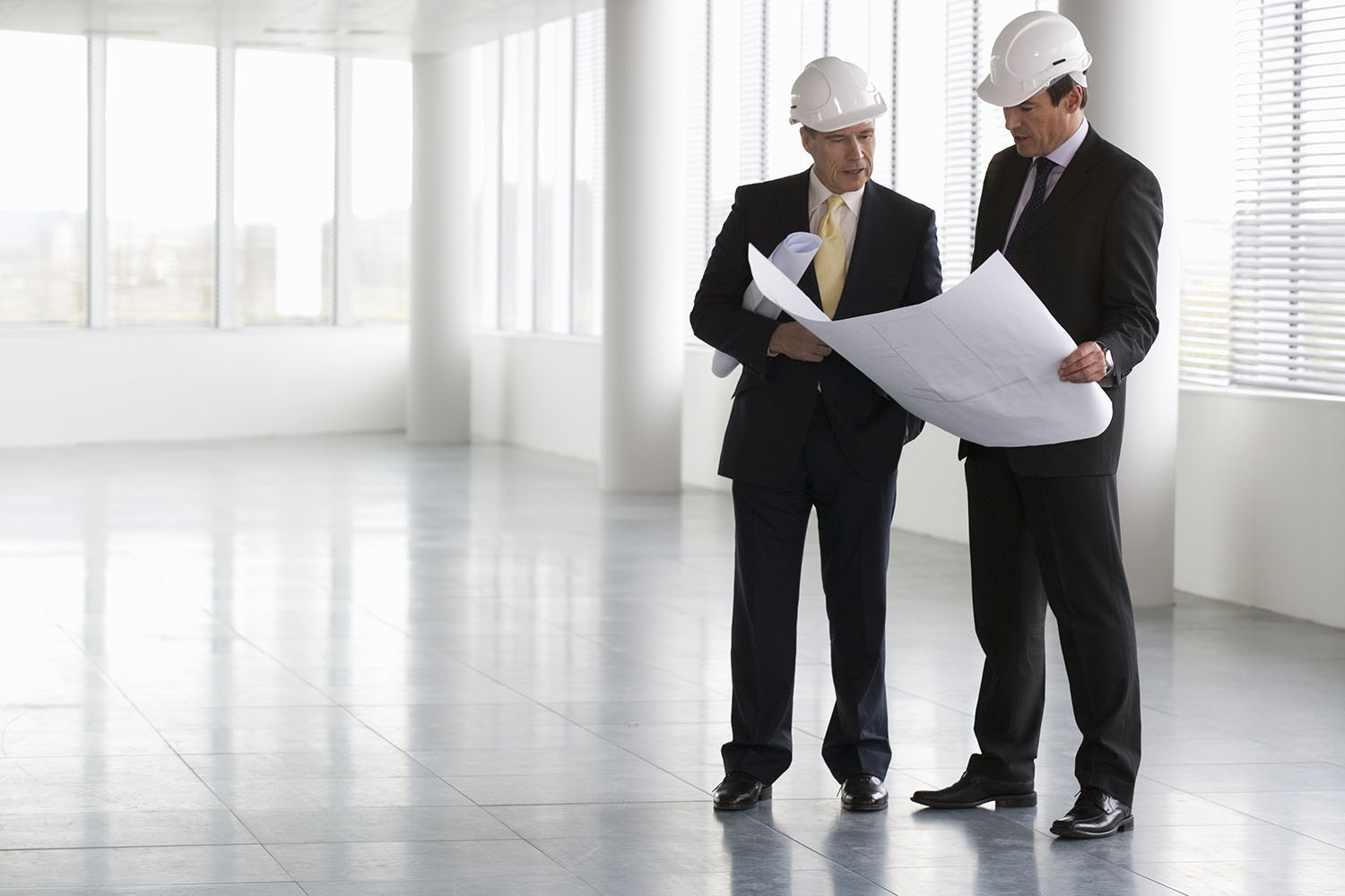 Men in hard hats looking at drawing plans